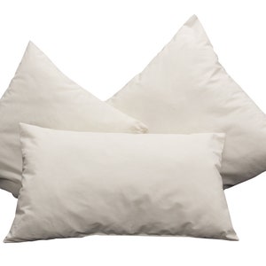 Könnte beinhalten: Drei weiße Kissenbezüge, in Dreiecksform angeordnet, wobei der obere Kissenbezug die beiden unteren Kissenbezüge leicht überlappt.