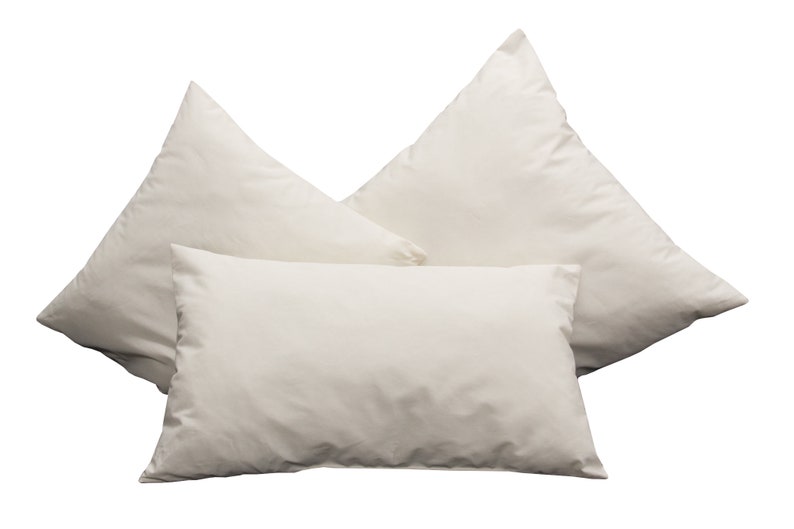 May include: Three white pillowcases, arranged in a triangular shape, with the top pillowcase slightly overlapping the two bottom pillowcases.