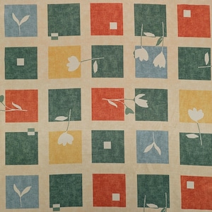 Può includere: Un motivo ripetuto di quadrati in vari colori, tra cui rosso, verde, giallo e blu, con uno sfondo beige. Ogni quadrato contiene un disegno floreale o geometrico bianco. Il design generale ricorda un tessuto o un patchwork.