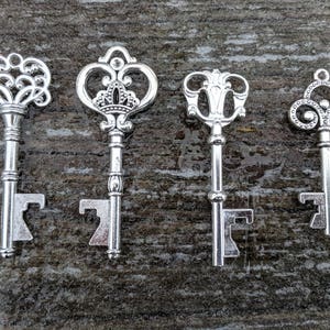 May include: Four silver-toned bottle openers shaped like antique keys. Each key has a unique design with intricate details.