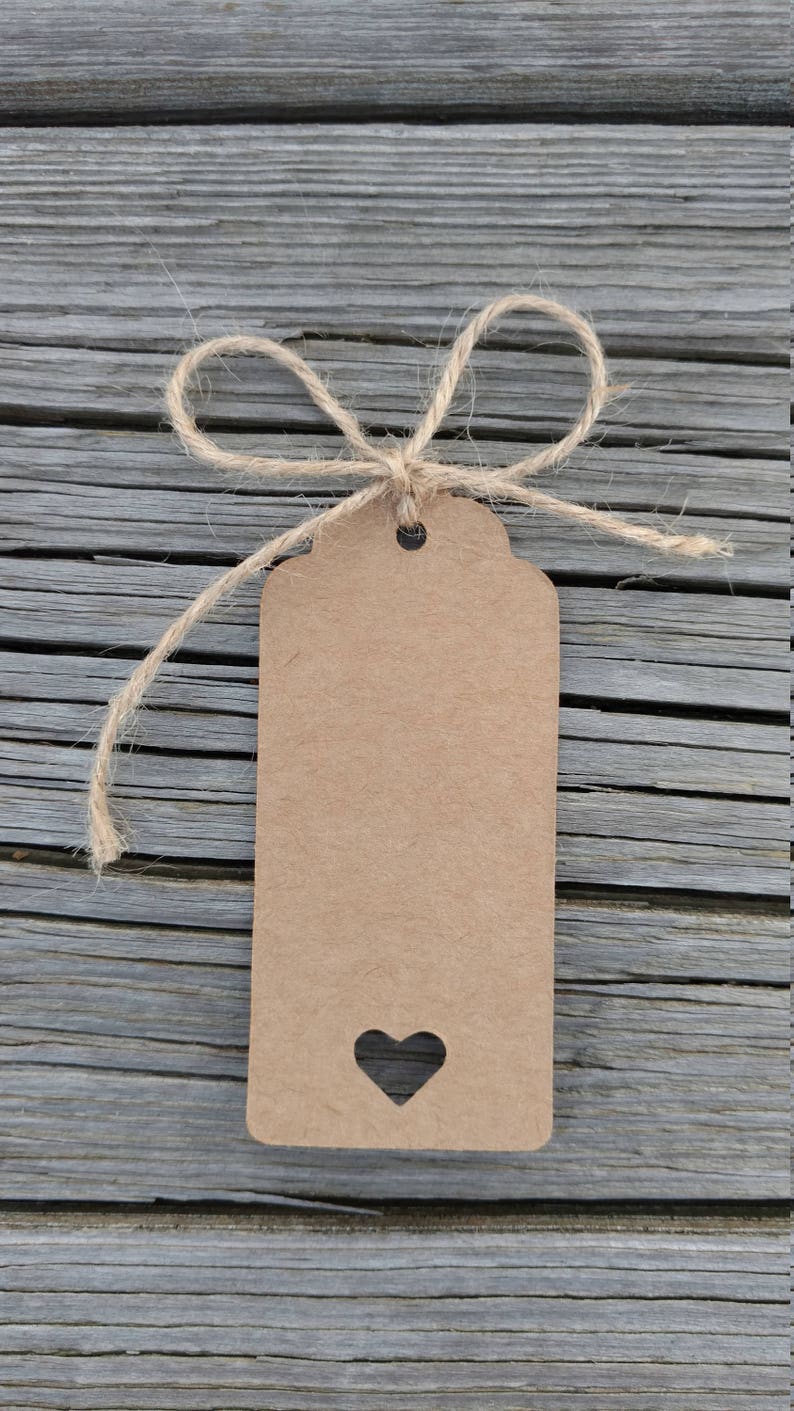 May include: A brown paper gift tag with a heart-shaped cutout tied with twine on a gray wooden background.