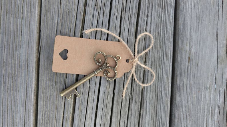 May include: A vintage-style key bottle opener with a brown paper tag tied with twine. The tag has a heart-shaped cutout.