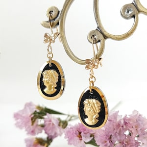 May include: Gold tone earrings with black cameo portraits and gold butterfly accents.