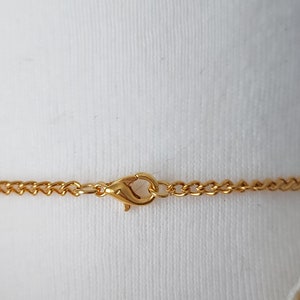 May include: Gold chain necklace with a lobster clasp closure.