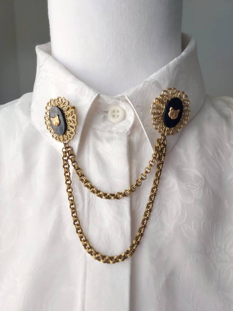 A marte old gold tone collar chain made with unused vintage parts: with two decorative circular filigree featuring black Shell with a brass miniature Cat face stamping on each. They have two sturdy chains linked to each filigree.