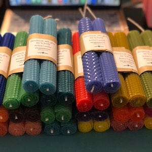 Puede incluir: Surtido de velas de cera de abeja de colores, enrolladas y agrupadas. Cada vela está etiquetada con "Handmade with love by Wendy, Rolled Candles, Ingredients".