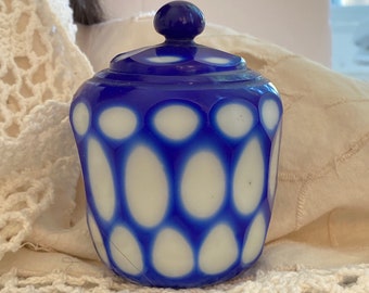 May include: A small blue and white glass jar with a lid. The jar has a pattern of white circles on a blue background.