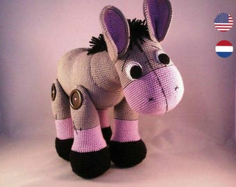 May include: A handmade crochet donkey toy in shades of gray, pink, and black. The donkey has large ears with purple interiors, button joints, and a pink muzzle. The name "halline" is written in red cursive above the donkey.