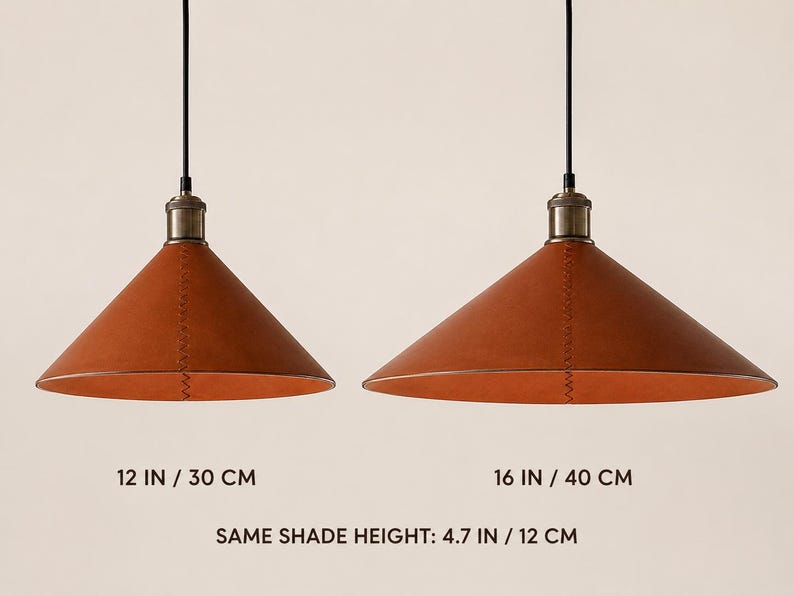 May include: Two conical pendant lights with brown leather shades and visible stitching, suspended by black cords from metallic fixtures. The left light measures 12 inches wide, the right 16 inches wide, and both have a shade height of 4.7 inches.
