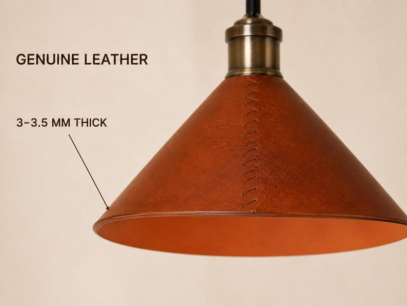 May include: A conical pendant lamp shade crafted from brown genuine leather, 3-3.5 mm thick, featuring visible cross-stitching along the side and a metallic brass-toned fixture at the top. The interior of the shade is a smooth, lighter orange tone.