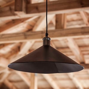 May include: A matte black conical pendant light fixture suspended by a thin black cord. The shade features a visible stitched seam running vertically along one side, connecting to a metallic silver-toned hardware fitting at the top center.