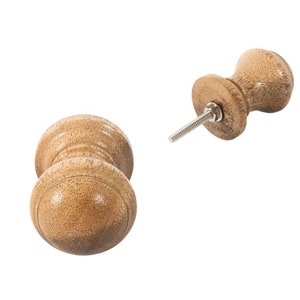 May include: Two wooden knobs with a round shape and a cylindrical base. The knobs are a light brown colour and have a smooth finish.