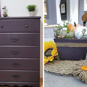 May include: A five-drawer chest of drawers painted in a deep purple colour with black drawer pulls. The chest of drawers has a slightly curved bottom edge and sits on a wooden floor.