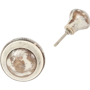 Peut inclure: Un bouton en céramique blanc et brun avec une finition vieillie. Le bouton est rond avec un bord surélevé et un cercle plus petit au centre.