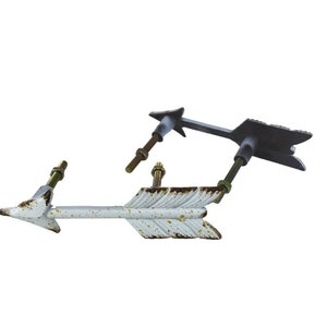 Peut inclure: Deux poignées de tiroir en forme de flèche, l'une en blanc avec des accents dorés et l'autre en noir avec des accents argentés. Les deux ont une finition rustique et vieillie.