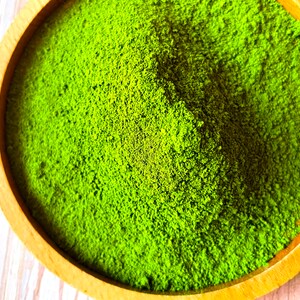 Puede incluir: Un taz&oacute;n de madera lleno de polvo de matcha verde brillante.