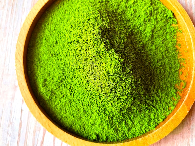 Puede incluir: Un taz&oacute;n de madera lleno de polvo de matcha verde brillante.