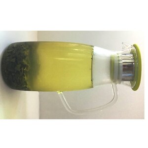 May include: A clear glass pitcher with a green lid and a stainless steel strainer. The pitcher is filled with green tea and tea leaves.