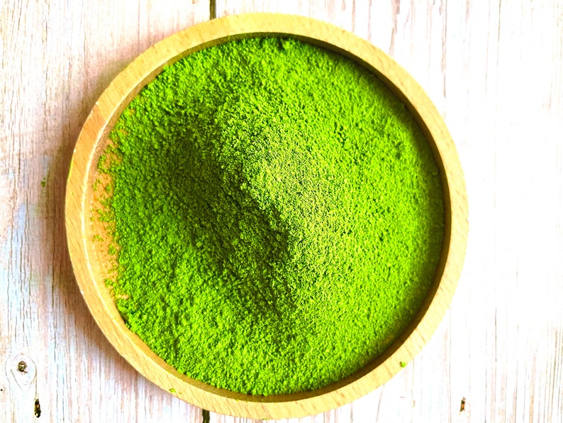 Puede incluir: Un taz&oacute;n de madera lleno de polvo de matcha verde brillante.