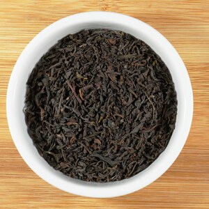 May include: A white ceramic bowl filled with loose black tea leaves.