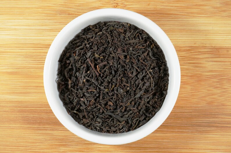 May include: A white ceramic bowl filled with loose black tea leaves.