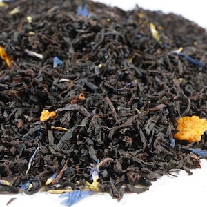 May include: A close-up of a blend of black tea leaves, blue cornflower petals, and orange peel pieces.