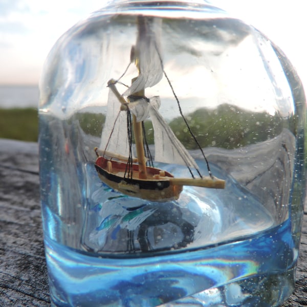 Sloop, Ship in a bottle sailing on a blue sea