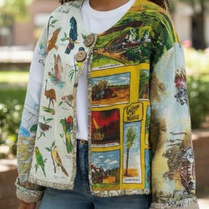 May include: A patchwork jacket with a vibrant design, featuring illustrations of birds, landscapes, and text. The jacket has two large wooden buttons and a beige trim. It is worn over a white long-sleeved top and blue jeans. The jacket's design is eye-catching.