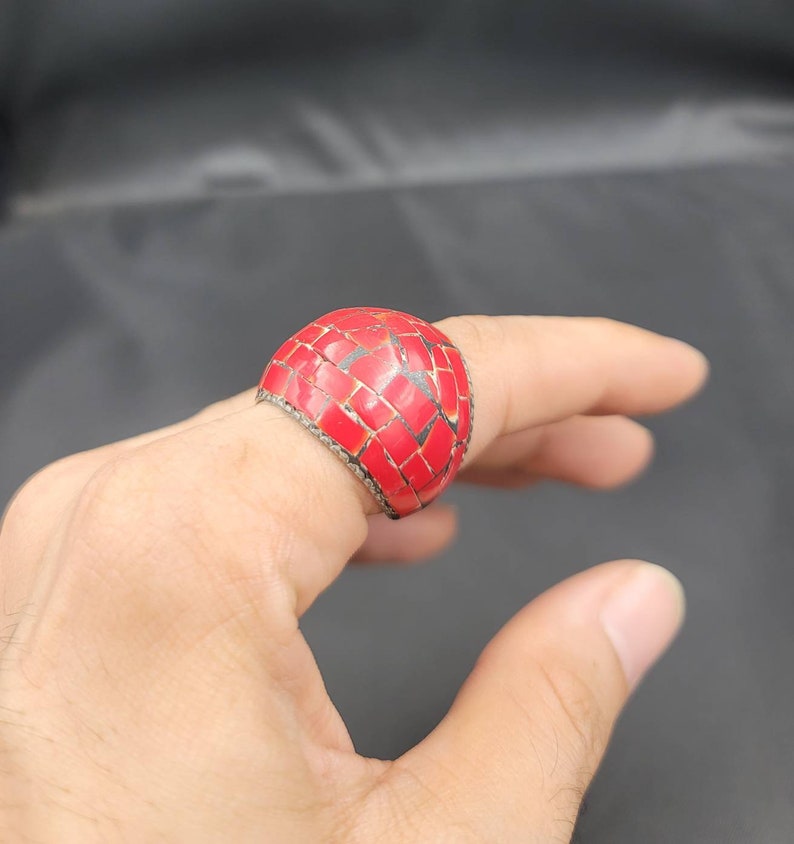 Puede incluir: Un anillo de mosaico rojo con una banda plateada. El anillo est&aacute; hecho de peque&ntilde;os cuadrados rojos que est&aacute;n engastados en una banda plateada.