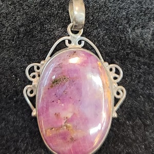 Może przedstawiać: Srebrny wisiorek z owalnym różowym i białym kamieniem szlachetnym osadzonym w filigranowym wzorze.