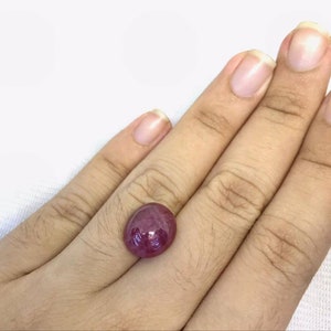 Op de afbeelding: Een dieprode ovale edelsteen met een stervormig patroon.