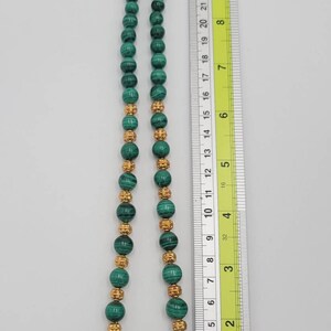 May include: A green malachite bead necklace with gold accents. The necklace is approximately 18 inches long and features a clasp closure.