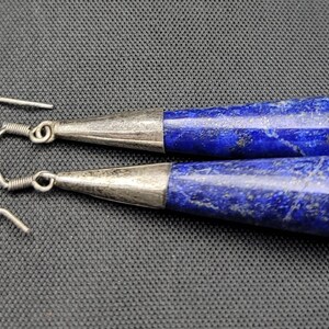 May include: A pair of silver dangle earrings with blue lapis lazuli teardrop-shaped stones.
