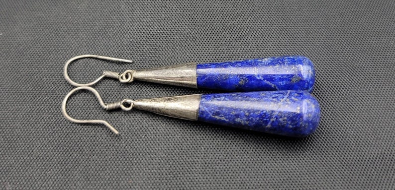 May include: A pair of silver dangle earrings with blue lapis lazuli teardrop-shaped stones.