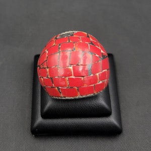 Puede incluir: Un anillo redondo de mosaico rojo y negro. El anillo est&aacute; hecho de peque&ntilde;as piezas cuadradas de material rojo y negro.