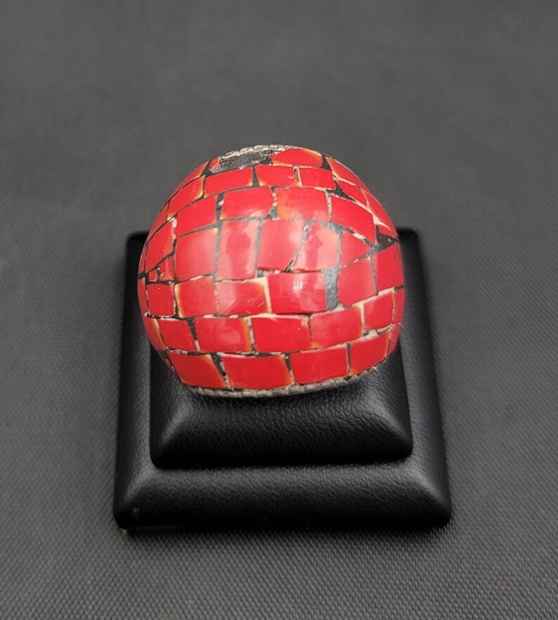 Puede incluir: Un anillo redondo de mosaico rojo y negro. El anillo est&aacute; hecho de peque&ntilde;as piezas cuadradas de material rojo y negro.