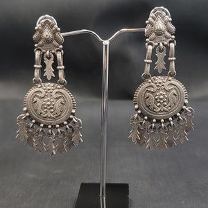 Può includere: Un paio di orecchini d'argento con intricati disegni floreali e di uccelli. Gli orecchini sono appesi a un supporto d'argento.