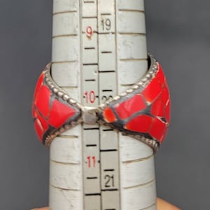 Puede incluir: Un anillo rojo y plateado con un dise&ntilde;o de mosaico. El anillo se est&aacute; midiendo en una regla, y el tama&ntilde;o es de aproximadamente 10.5 pulgadas.
