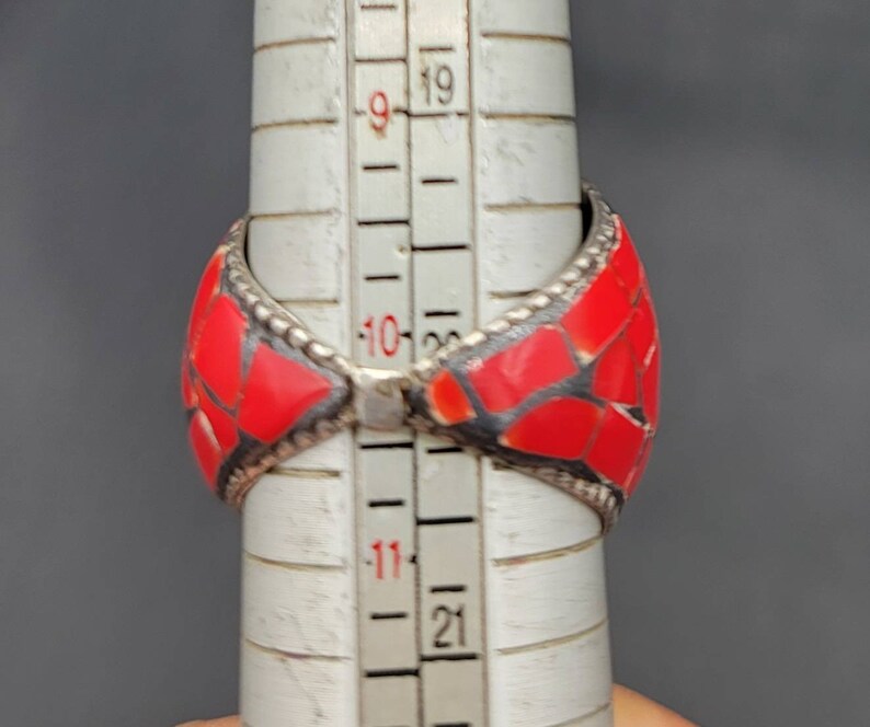 Puede incluir: Un anillo rojo y plateado con un dise&ntilde;o de mosaico. El anillo se est&aacute; midiendo en una regla, y el tama&ntilde;o es de aproximadamente 10.5 pulgadas.