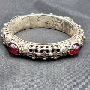 Könnte beinhalten: Silberarmband mit filigranem Design und zwei roten Glassteinen.