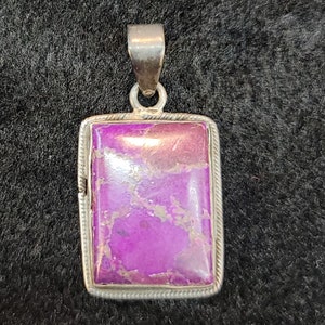 Może przedstawiać: Srebrny wisiorek z prostokątnym, fioletowym kamieniem osadzonym w srebrnej oprawie.