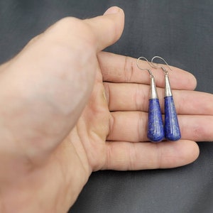 May include: A pair of silver dangle earrings with blue lapis lazuli teardrop-shaped stones.