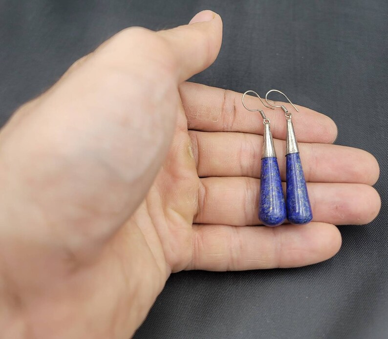 May include: A pair of silver dangle earrings with blue lapis lazuli teardrop-shaped stones.