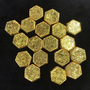 以下が含まれることがあります： 花柄の金色の六角形のタイル15枚が蜂の巣の模様に並んでいます。タイルは対称的なパターンで配置されています。