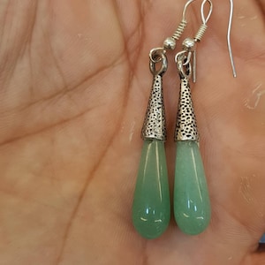 Pu&ograve; includere: Un paio di orecchini pendenti in argento con gocce di pietre preziose verdi. Gli orecchini hanno un design in argento testurizzato nella parte superiore della goccia.