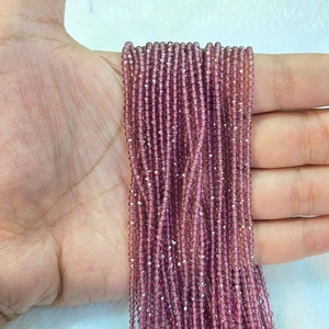 May include: A strand of small, faceted, amethyst-colored beads. The beads are strung on a clear thread and are approximately 2mm in diameter.