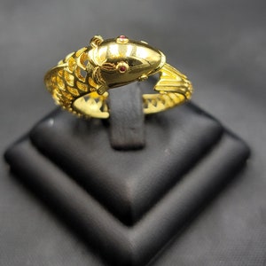 Op de afbeelding: Gouden ring met een gedetailleerd visontwerp en twee rode edelstenen voor de ogen.