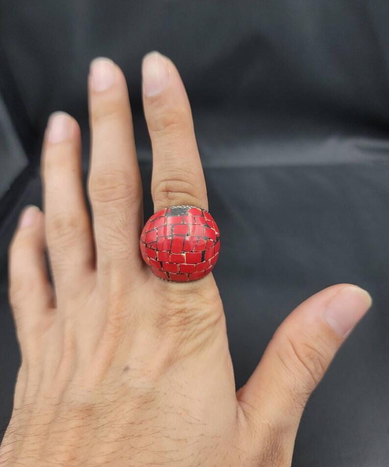 Puede incluir: Un anillo rojo con un dise&ntilde;o de mosaico. El anillo est&aacute; hecho de peque&ntilde;as piezas cuadradas de material rojo.