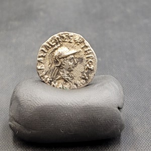 May include: Silver coin with a portrait of a person wearing a helmet and the inscription "IMP CAESAR AVG F AVG" around the edge.