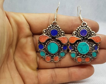 May include: A pair of silver dangle earrings with turquoise, coral, and lapis lazuli stones. The earrings have a unique, intricate design.